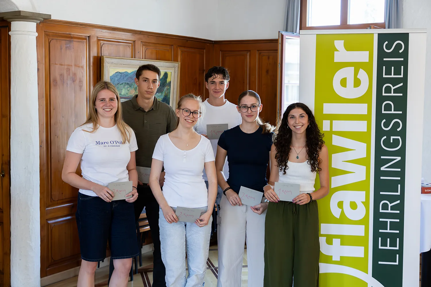 Die Gewinner:innen stehen vor einer Wand.